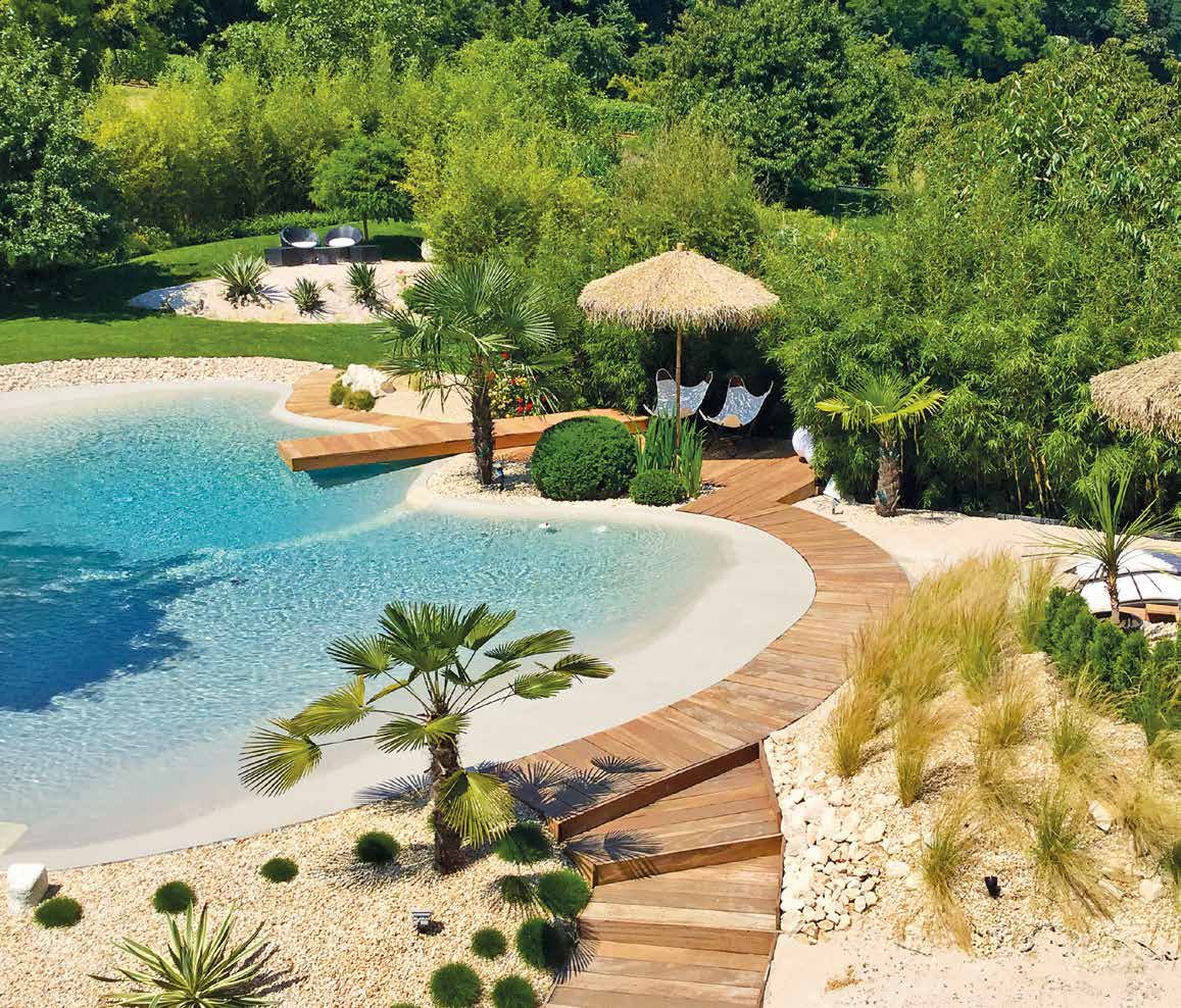 Piscina de arena Bio.design con solárium de madera y vegetación